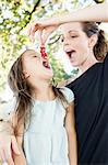 Mature woman feeding daughter redcurrants in park