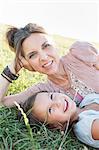 Mature woman and daughter reclining in park