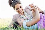 Mature woman and daughter reclining holding hands in park