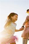 Mature woman and daughter holding hands and running in park