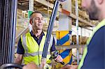 Supervisor instructing male forklift truck driver in distribution warehouse