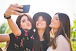 Three young female friends taking smartphone selfie in park