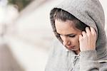 Female runner wearing grey hoody listening to earphone music