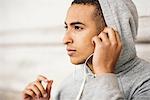 Male runner wearing grey hoody listening to earphone music