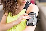 Cropped close up of female runner choosing music on smartphone armband