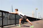 Runner stretching on riverfront, Wapping, London