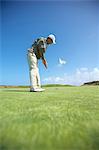 Low angle full length side view of golfer putting