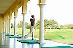 Golfer in archways practising golf swing looking away