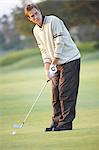 Golfer holding golf club preparing to take gold swing, looking away
