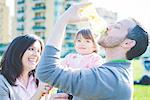 Mid adult man drinking toddler daughters baby bottle in park