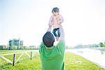Mid adult man lifting up toddler daughter in park