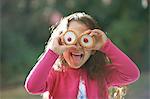 Portrait of girl with tartlets in front of her eyes in garden