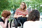 Female student in wheelchair chatting to friends on college campus