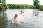 Teenage boy and sister splashing in rural lake