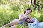 Young couple lying on grass eating strawberries smiling