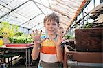 Boy in greenhouse showing his dirty hands