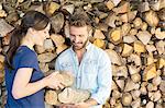 Young couple selecting chopped firewood from pile