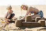 Mother and son making sandcastle on beach