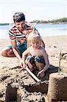 Father and son on beach making sandcastle