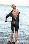 Young woman putting on wetsuit