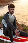 Surfer sits on surfboard