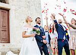 Guests throwing rose petals on bride and groom