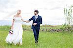 Bride and groom holding hands in the meadow