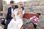 Bride and groom on bench smiling happily