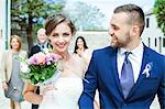 Bride and groom walking with family in background