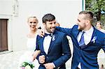 Bridegroom and wedding guest embracing