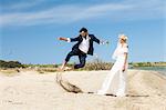 Bride and bridegroom on beach having fun