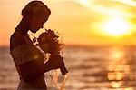 Bride smelling bouquet against sunset