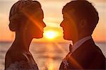 Bride and bridegroom face to face against sunset