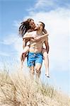 Man giving girlfriend piggyback ride on beach