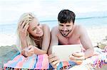 Young couple using digital tablet on beach