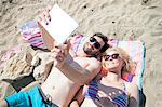 Young couple using digital tablet on beach