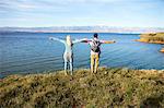 Young couple standing on cliff arms outstretched