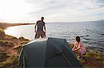 Young couple building up tent on water's edge