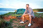 Young man at campsite day dreaming