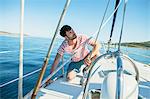 Man adjusting rigging on sailboat, Adriatic Sea