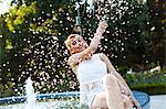 Young woman in hippie style fashion splashing water