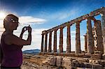 Tourist taking photo of Temple of Poseidon, Cape Sounion, near Athens, greece, Europe