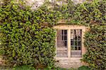 An old house and window is surrounded by the colours of spring in the village of Castle Combe, Wiltshire, England, United Kingdom, Europe