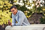 A man leaning on a parapet looking at a smart phone