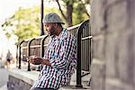 A man leaning on a railing, looking at a smart phone