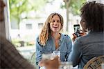 A woman talking a photograph of a friend using a smart phone.