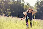 A child, a young girl in straw hat in a meadow of wild flowers in summer.