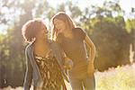 Two women walking through a field talking and laughing.