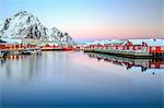 Pink sunset over the typical red houses reflected in the sea, Svolvaer, Lofoten Islands, Norway, Arctic, Scandinavia, Europe