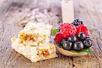 muesli bars with fresh berries in spoon on wooden background